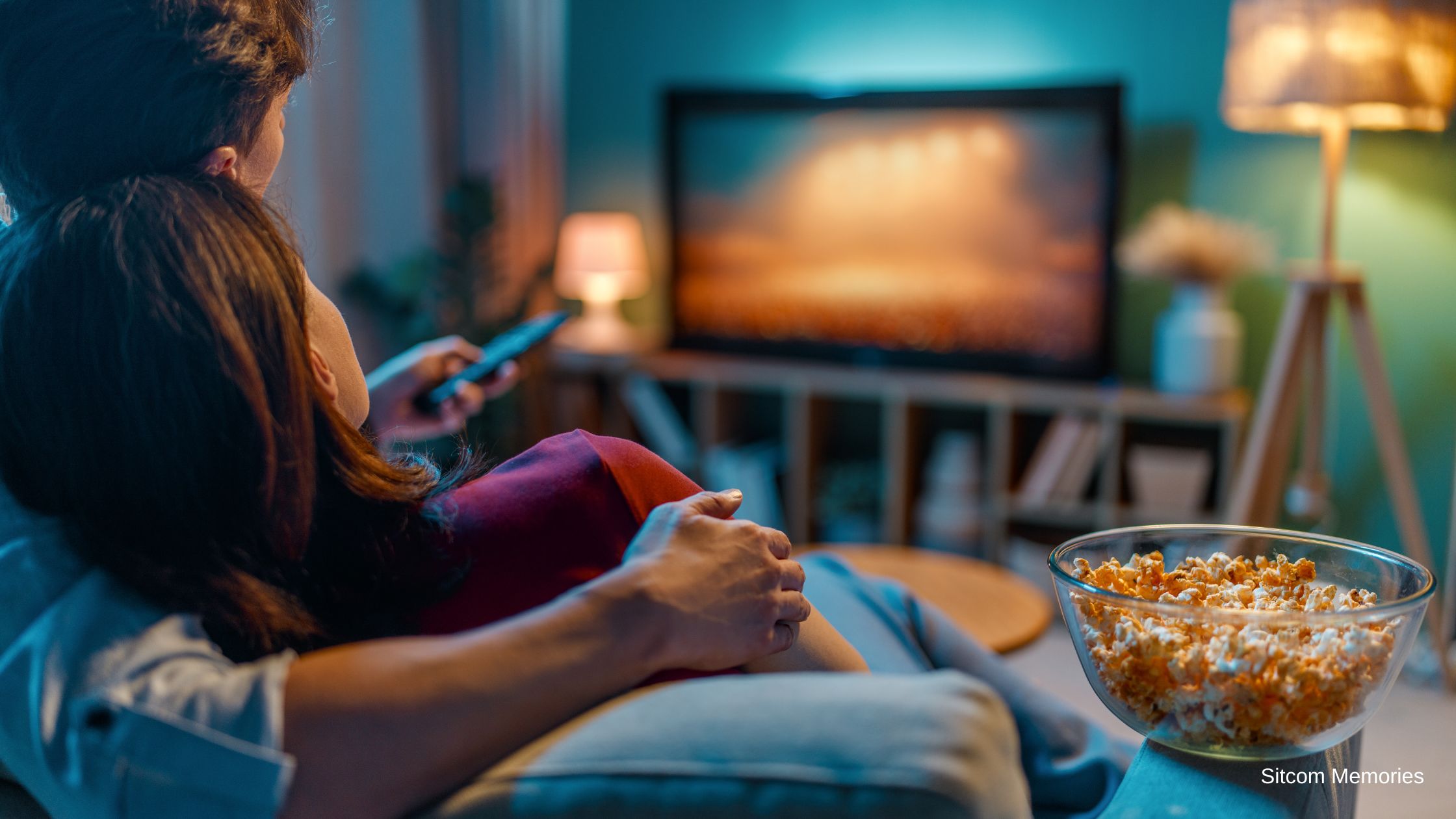 Man and woman snuggling and watching Tv.